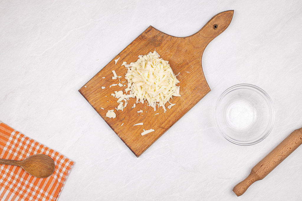 Top view of Grated Cheese on the wooden cutting board