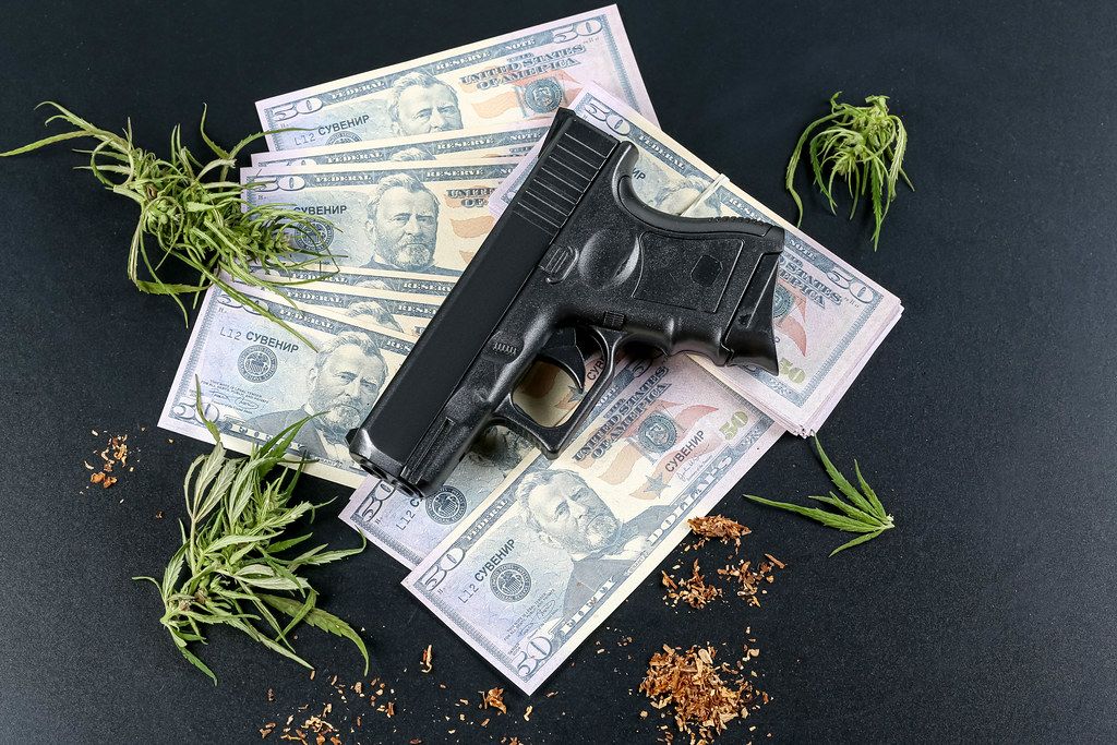 Top view of gun, money and hemp on black background