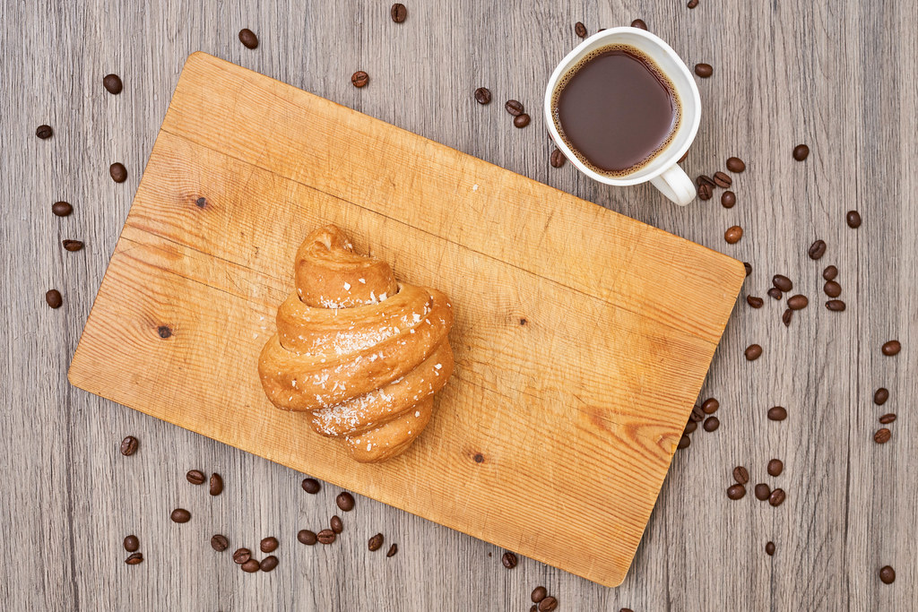 Top view of homemade croissant and hot black coffee on wooden table