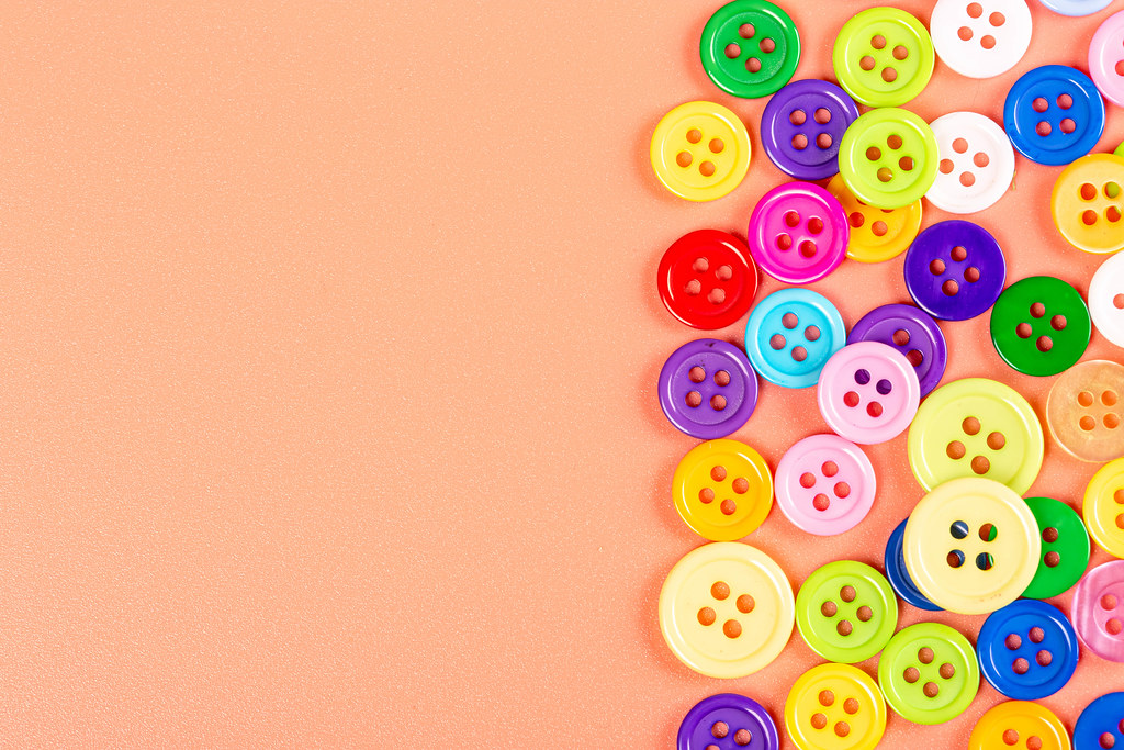Top view of multicolored buttons on orange background