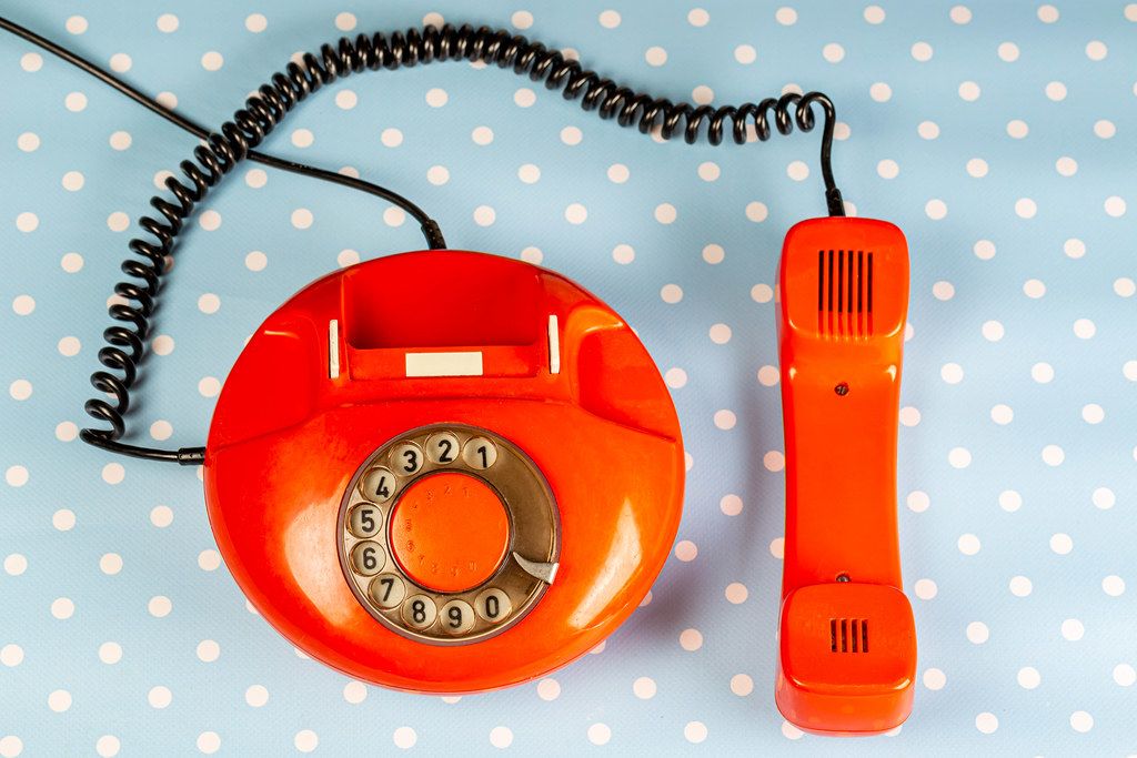 Top view of red vintage phone with handset on blue background