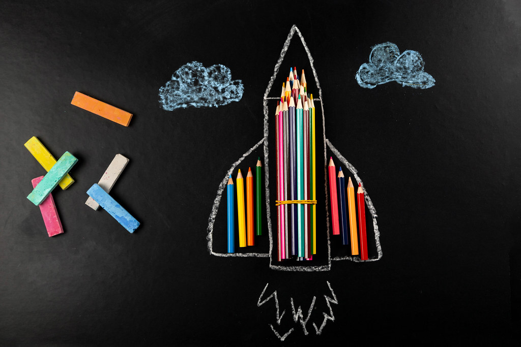 Top view, plane made of colored pencils with crayons on black background