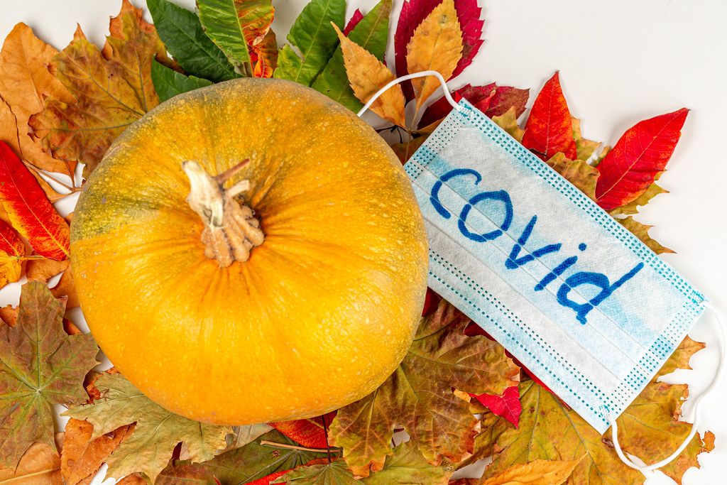 Top view, pumpkin and medical mask on an autumn leaf. Autumn quarantine concept