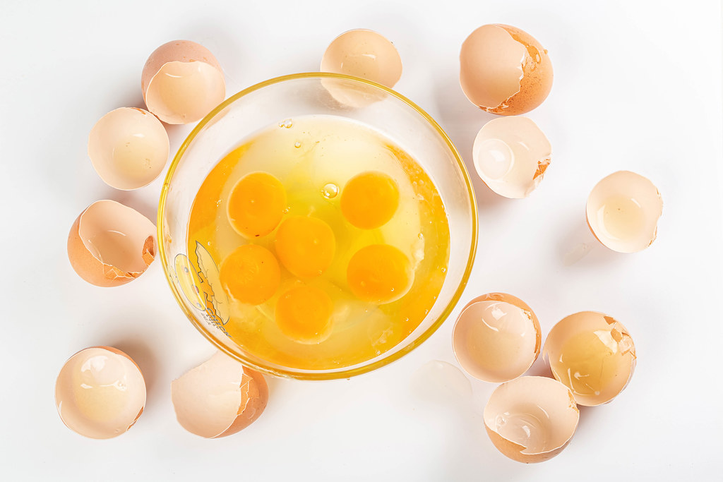Top view, raw eggs in bowl on white background with eggshell