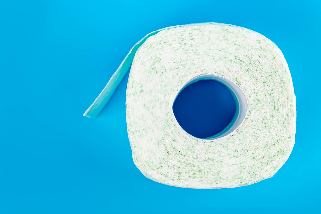 Top view, roll of toilet paper on blue