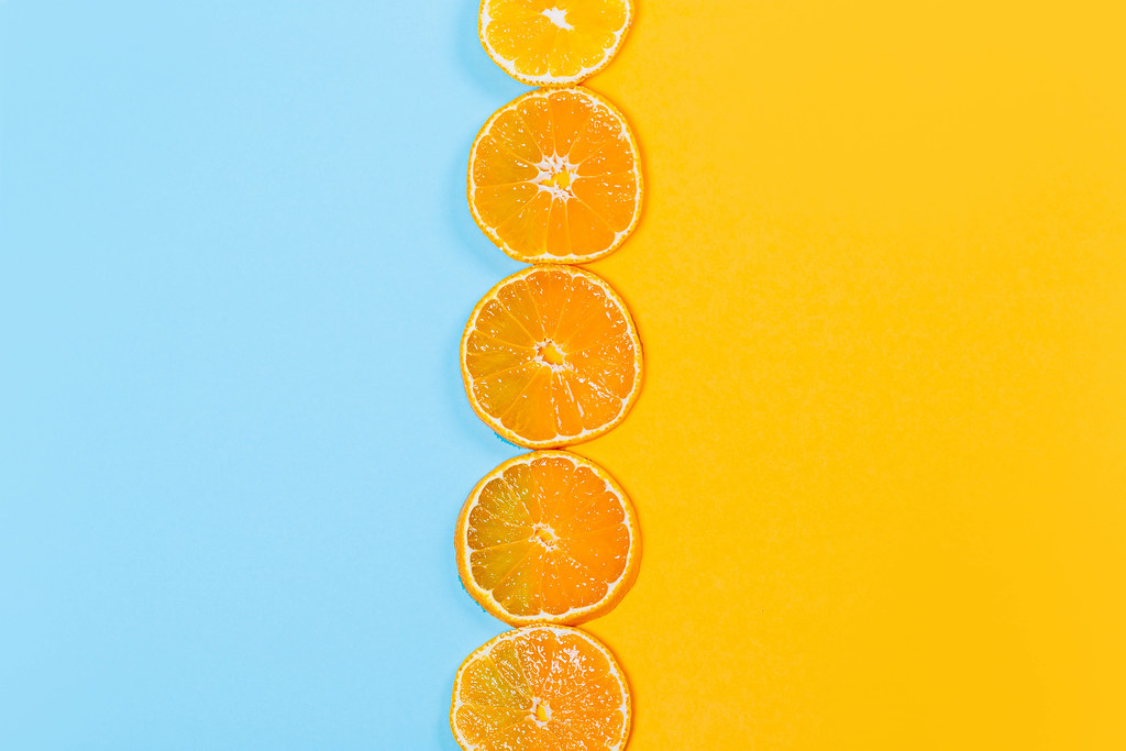 Top view, round pieces of tangerine on orange and blue background