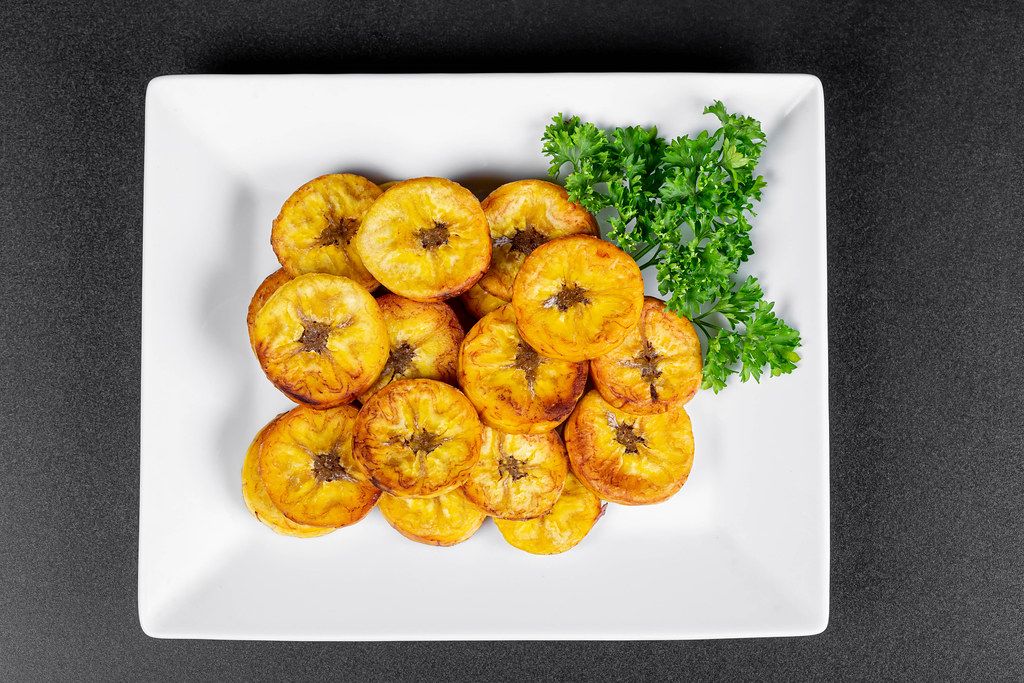 Top view, slices of fried plantain with fresh parsley