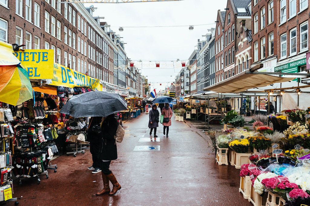 Tourists walking in the rain at Albert Cuyp street market in the city of Amsterdam