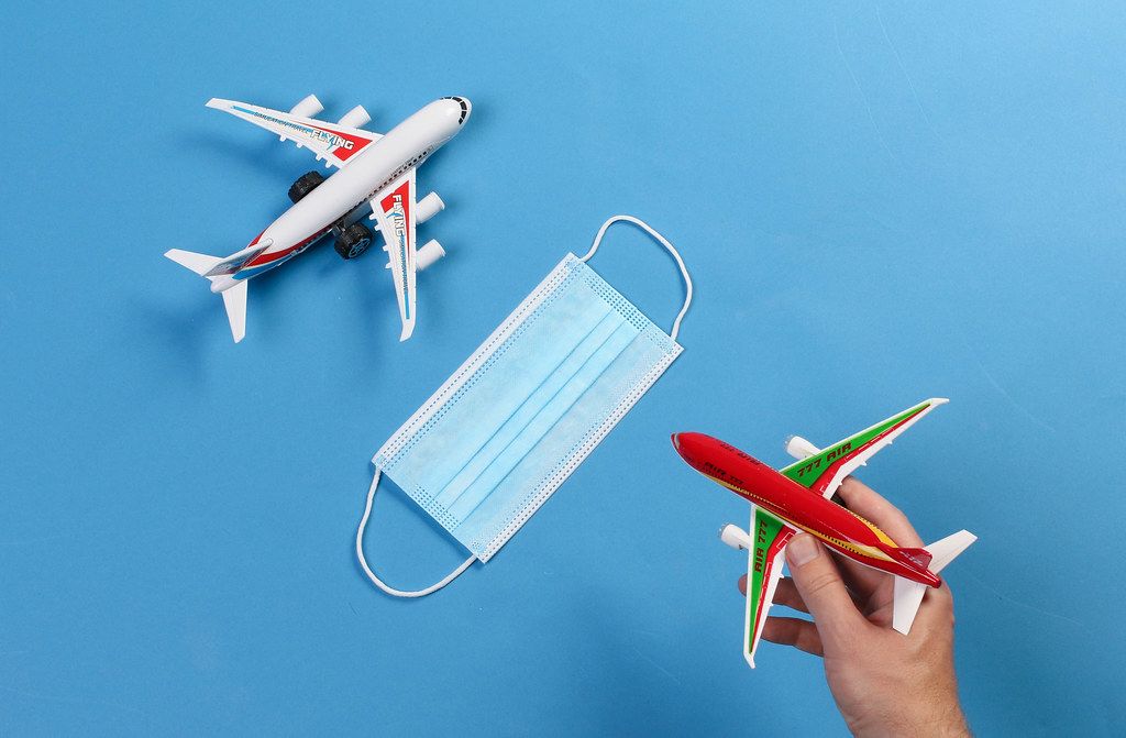 Toy airplanes with medical face mask on blue background