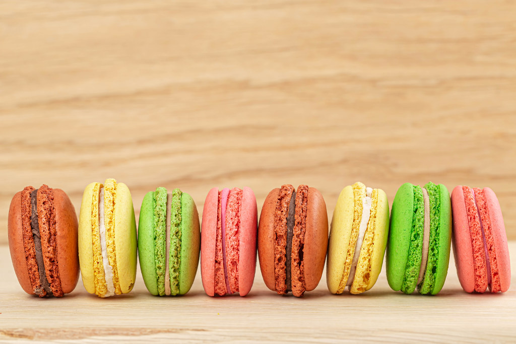 Traditional french colorful macaroons in a row on wooden background