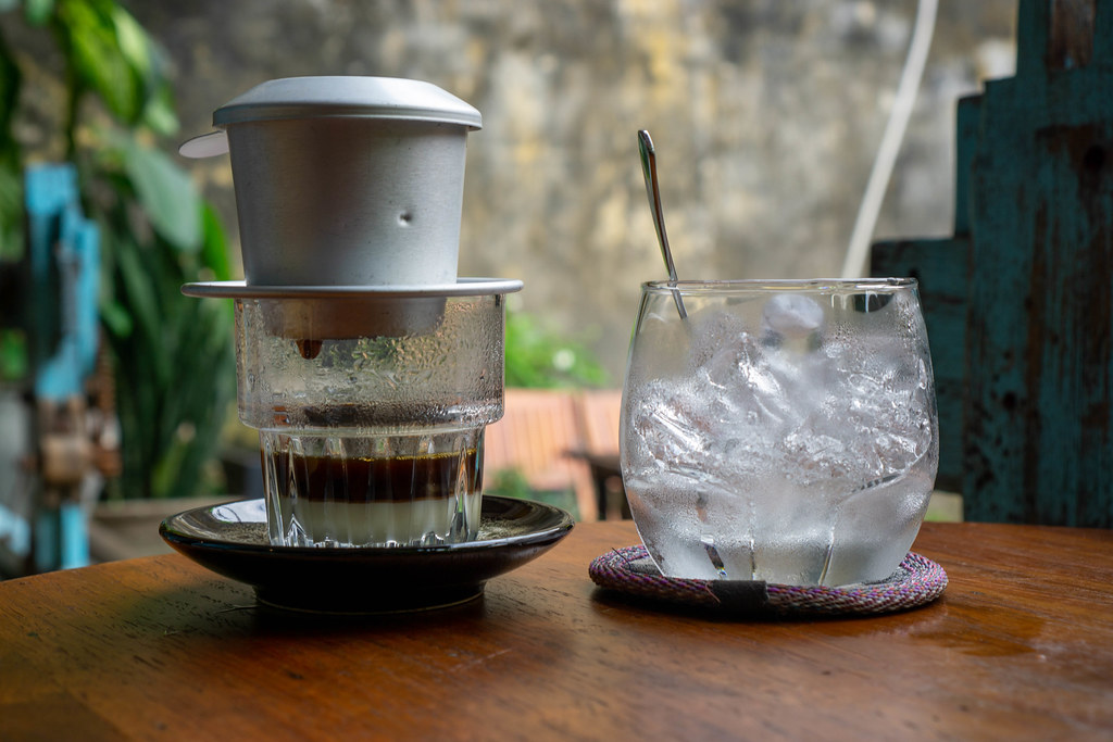 Traditional Vietnamese Drip Coffee with Condensed Milk in a Glas next to a Glas of Ice Cubes at a Cafe in Hoi An, Vietnam
