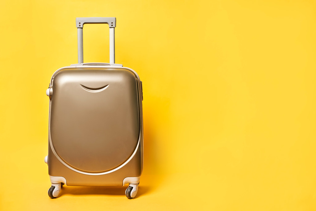 Travel suitcase on bright yellow background