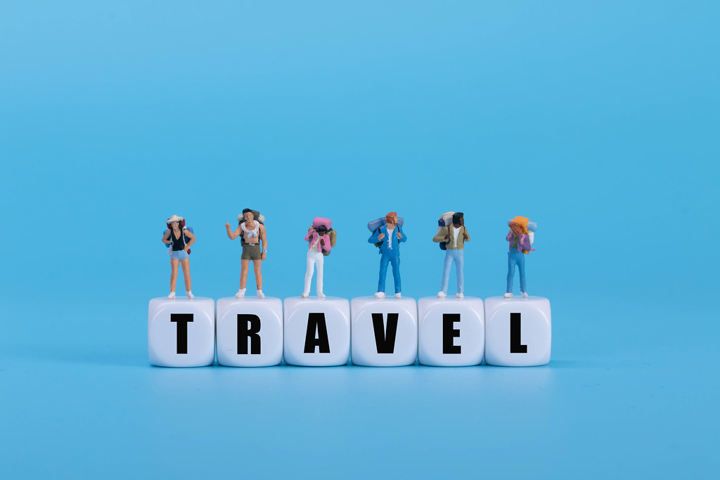 Travelers standing on white blocks with Travel text on blue background