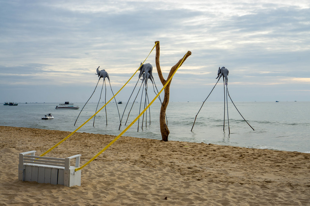 Tree Trunk connected with Wooden Chair for Photoshootings on a Sand Beach with Elephant Sculptures and Boats in the Sea in Phu Quoc, Vietnam