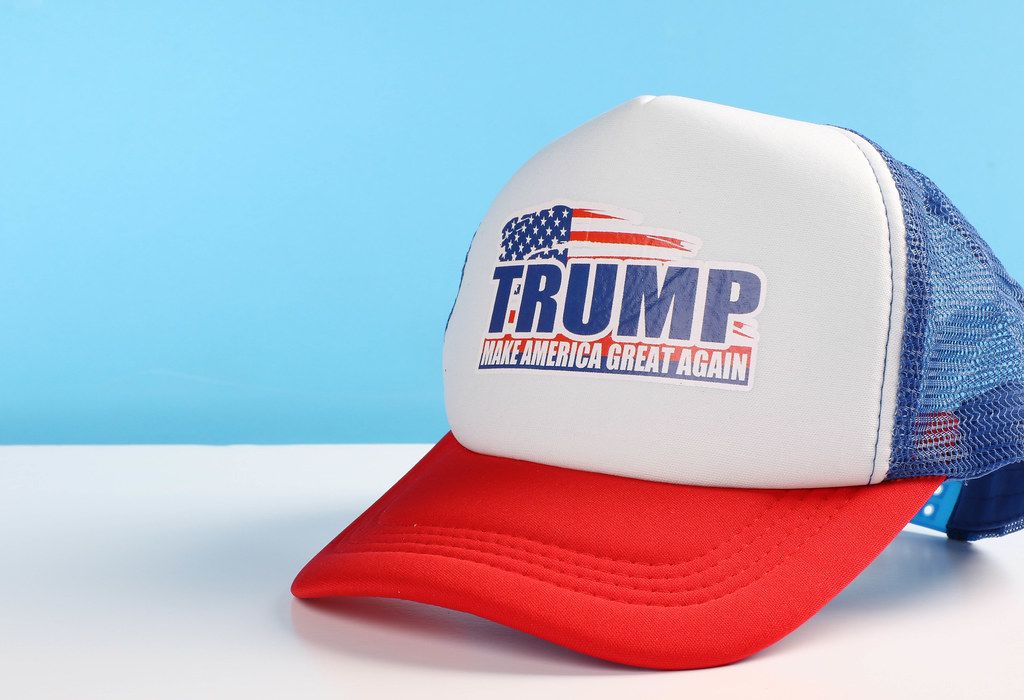 Trump classic trucker hat on white table with blue background