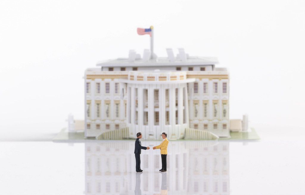 Two businessman shaking hands in front of White House