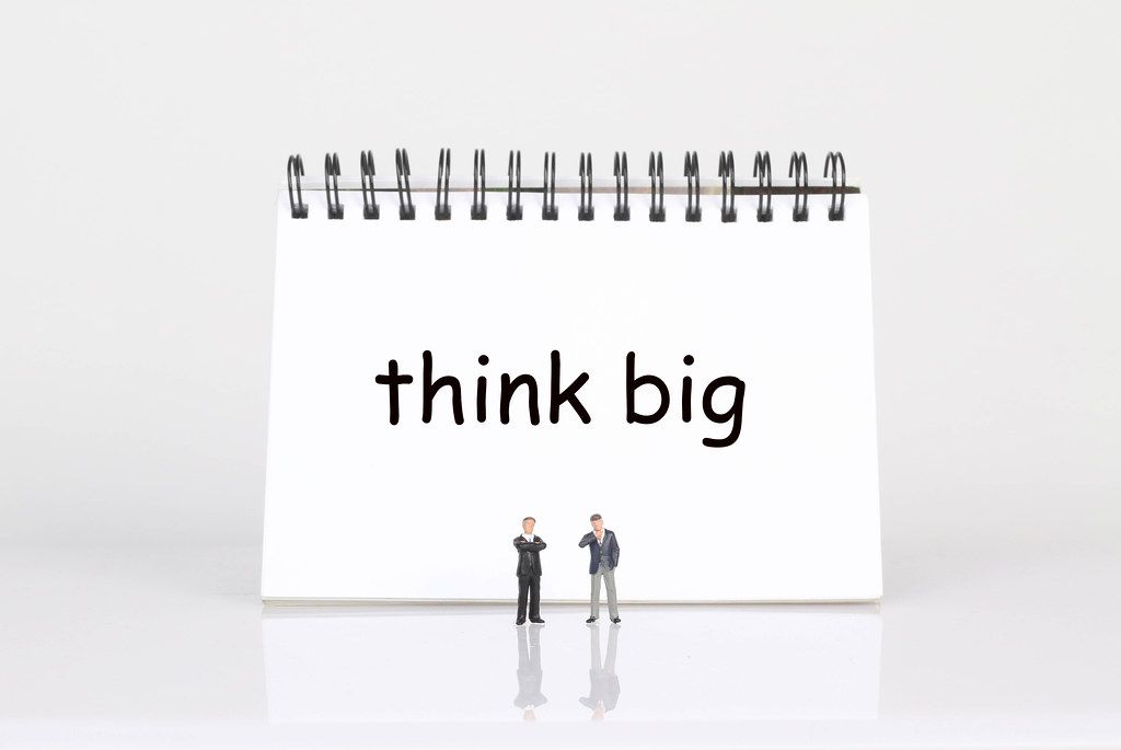 Two businessman standing in front of Think Big text
