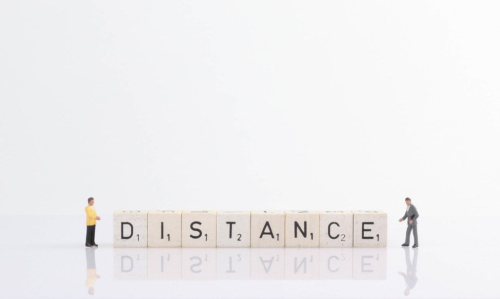 Two businessman standing next to Distance text on wooden blocks