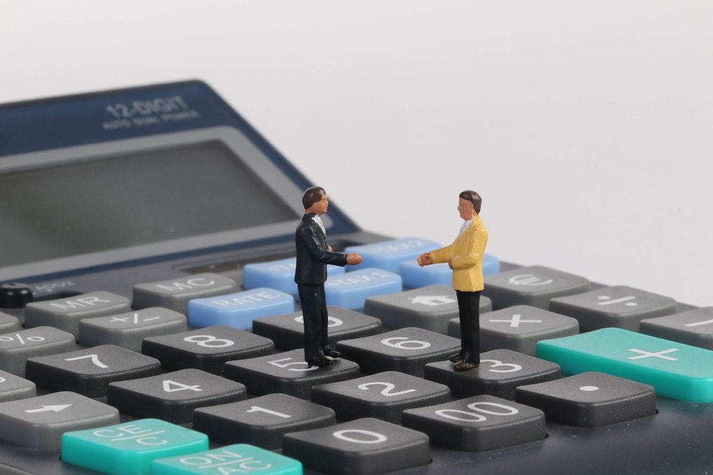 Two businessman standing on calculator