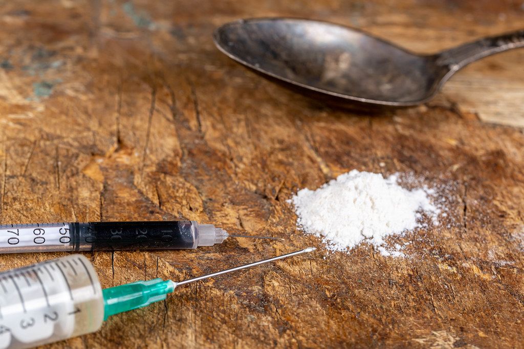 Two syringes, powder and spoon on old wooden background