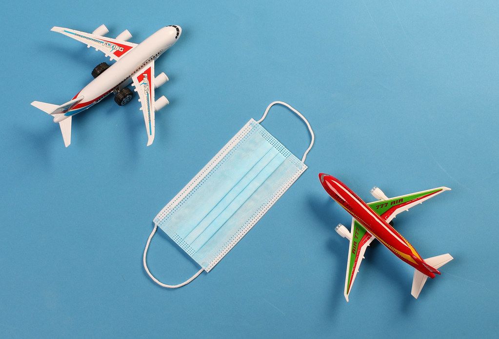 Two toy airplanes with protective mask on blue background
