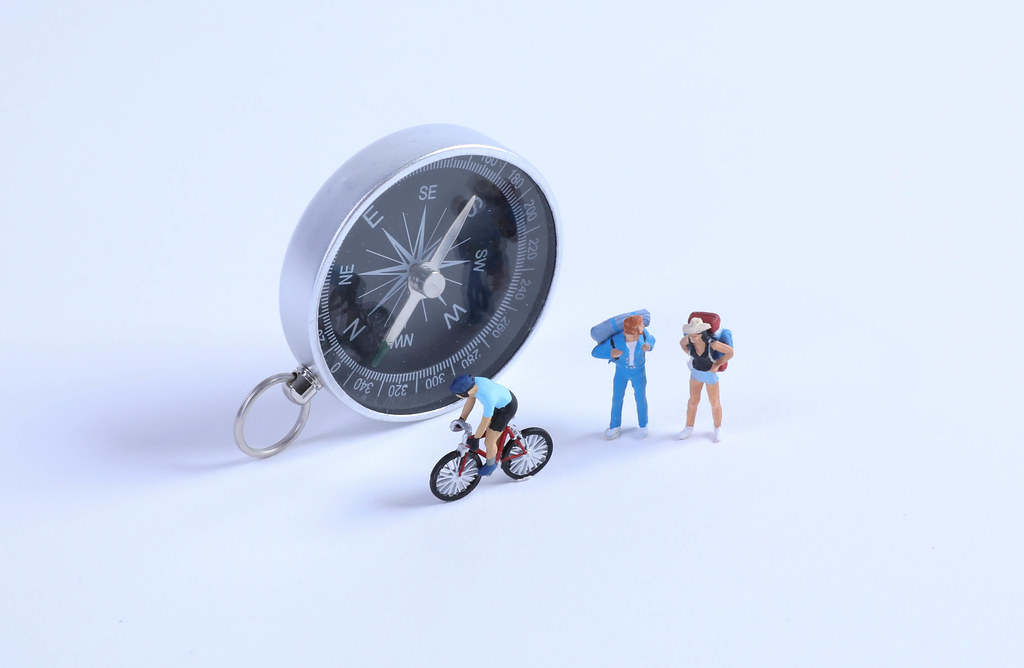 Two travelers and cyclist with compass on white background