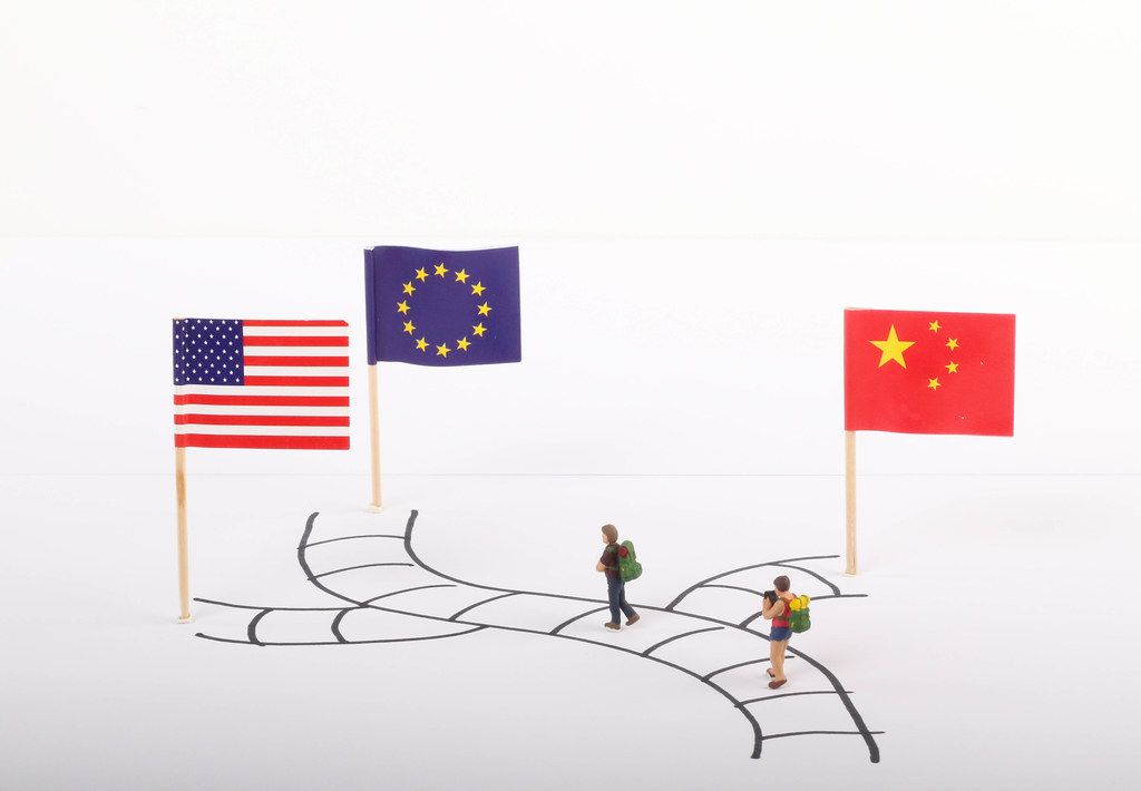 Two travelers standing on path with flags of USA, European Union and China