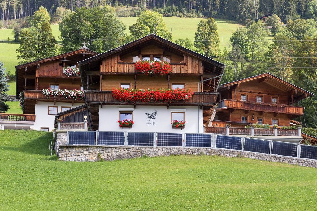 Typical wooden houses in Alpine style with pitched roof and balconies decorated by colourful flowers