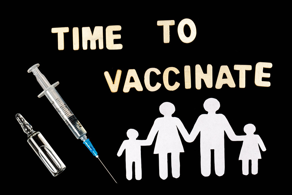 Vaccination time text on black with white family silhouette, syringe and ampoule