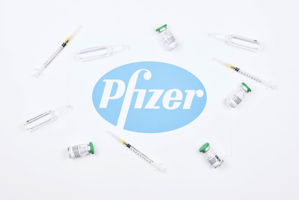 Vaccine doses and syringe for injection around the Pfizer logotype