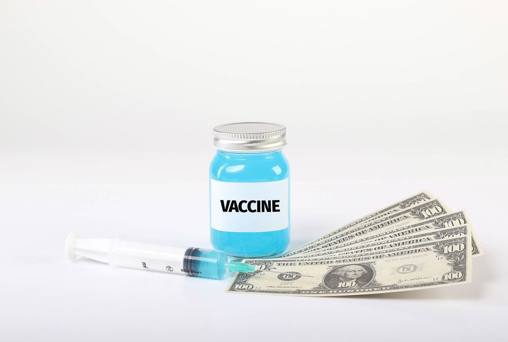 Vaccine with money and syringe on white background