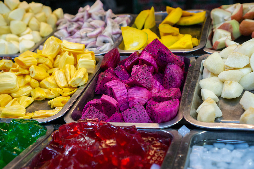 Verschiedene exotische Früchte wie Mango, Drachenfrucht und Jackfrucht bei einer Fruchtsalad Bar mit Selbstbedienung auf einem Nachtmarkt in Can Tho, Vietnam