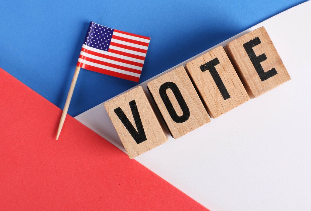 Vote word written on wooden blocks and American flag