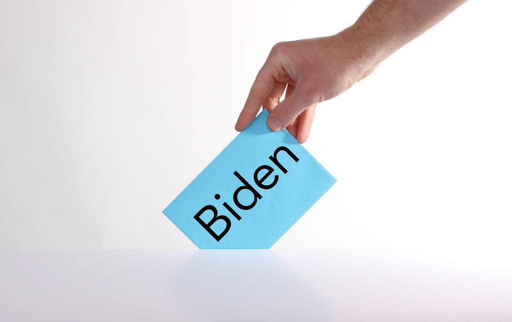 Voter holds blue envelope in a hand with Biden text