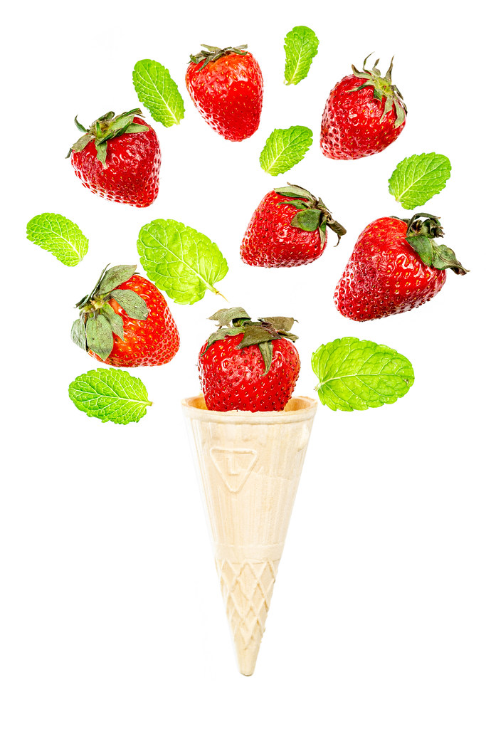 Waffle cone with strawberries and mint leaves on white
