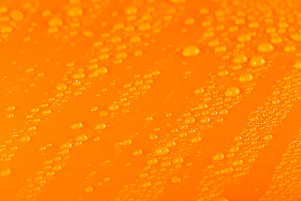 Water drops over orange background, close up