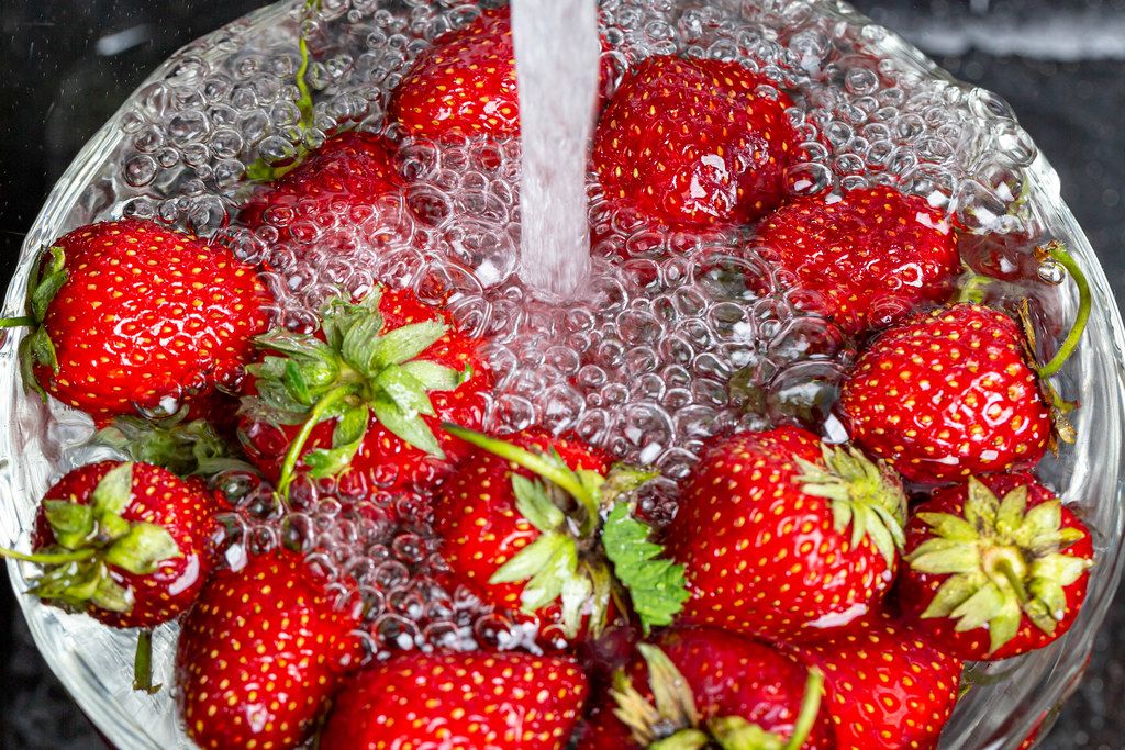 Water is poured into a bowl with strawberries