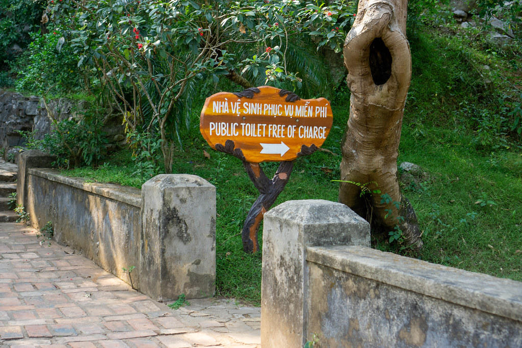 Wegbeschreibung zu einer öffentlichen Toilette auf einem Holzschild bei der Touristenattraktion Marble Mountains in Da Nang, Vietnam