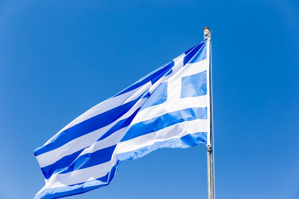 White and blue Greek flag in the wind against the blue sky
