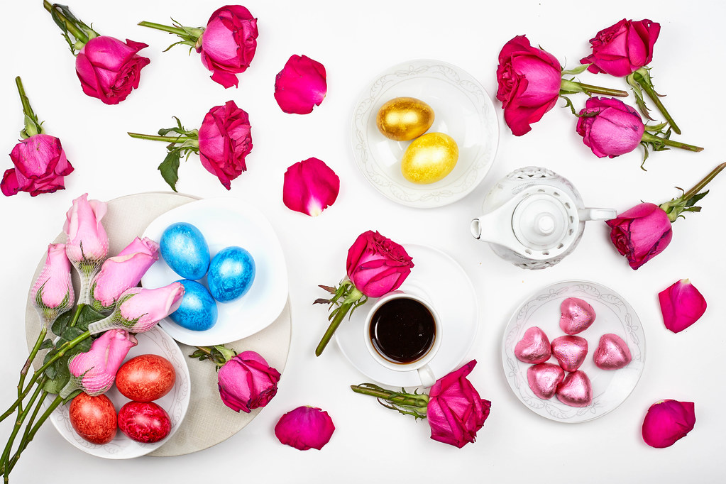 White background with romantic mood for Easter with dyed eggs, roses, chocolate hearts, a hot drink
