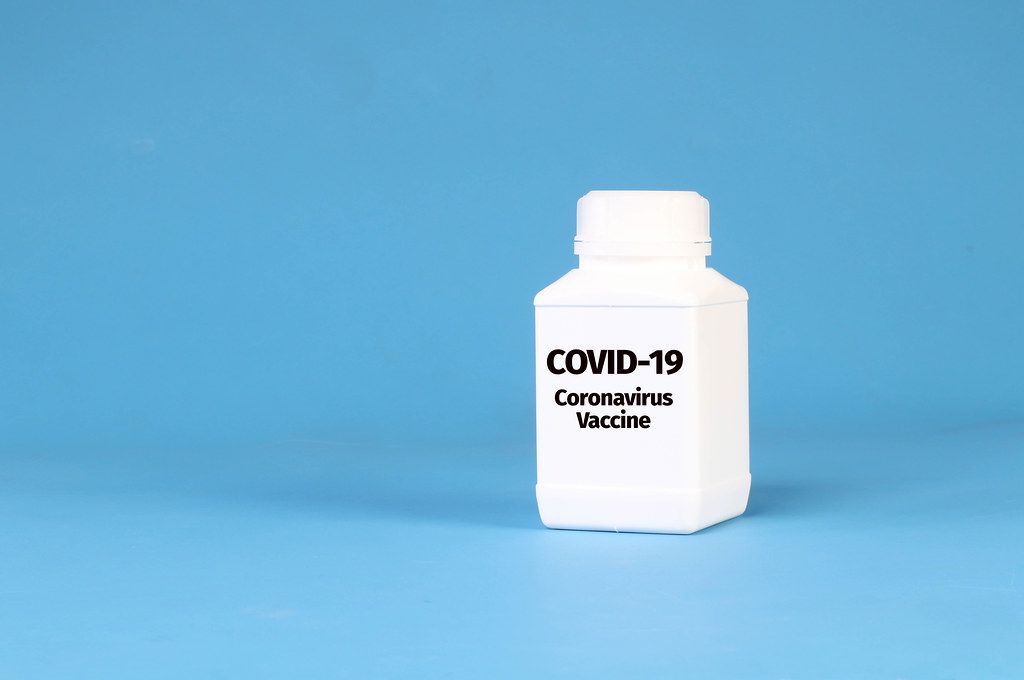White bottle with COVID-19 Coronavirus Vaccine text on blue background