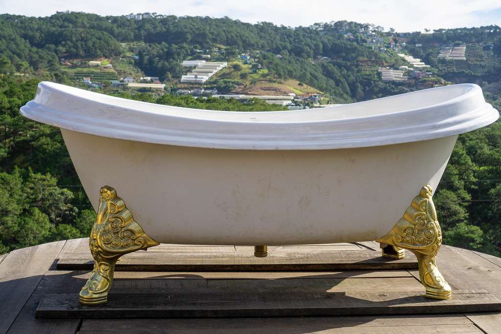 White Ceramic Bathtub with Golden Legs for Photoshoots on a Wooden Terrace of an Outdoor Cafe with a Mountain View in Da Lat, Vietnam