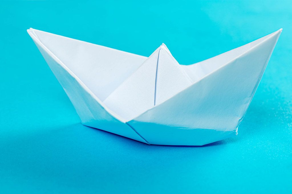 White paper ship on a blue background
