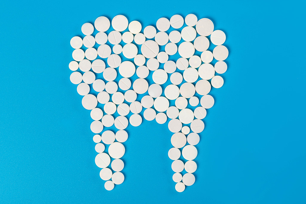 White tablets in the shape of a tooth on a blue background, the concept of healthy teeth