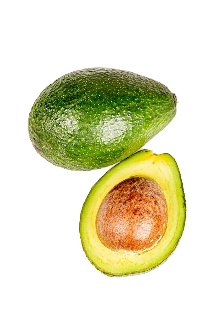 Whole and half avocado on a white background