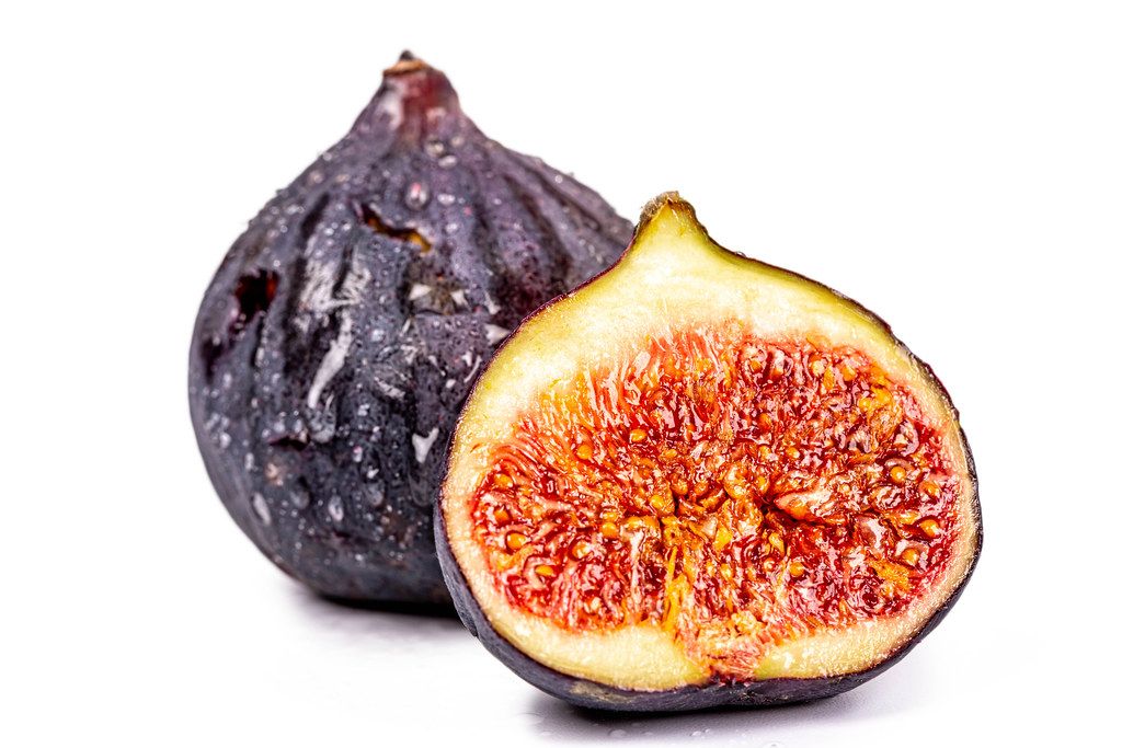 Whole and half fresh figs on white background