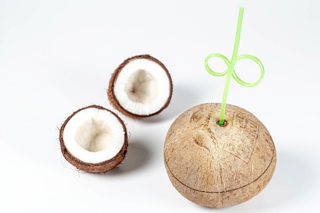 Whole coconut with a straw and halves coconut