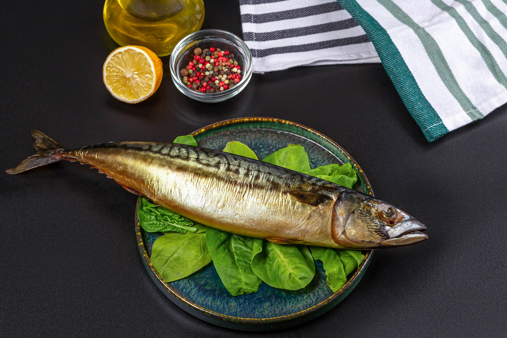 Whole smoked mackerel on a dark background with spices
