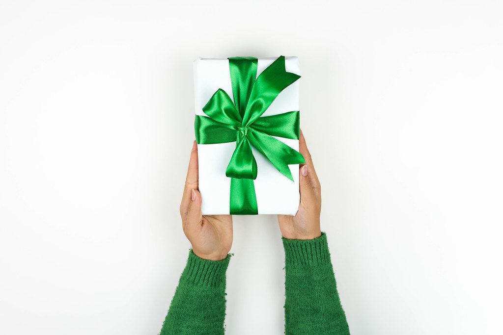 Woman giving a beautiful present with a green textile ribbon