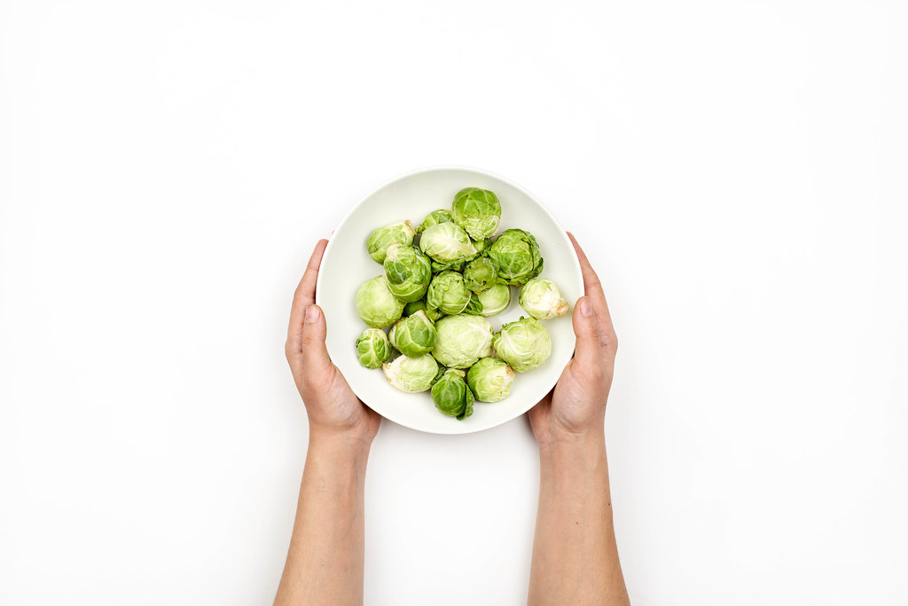 Woman hands holding a bowl of tiny cabbages also called Brussels sprouts